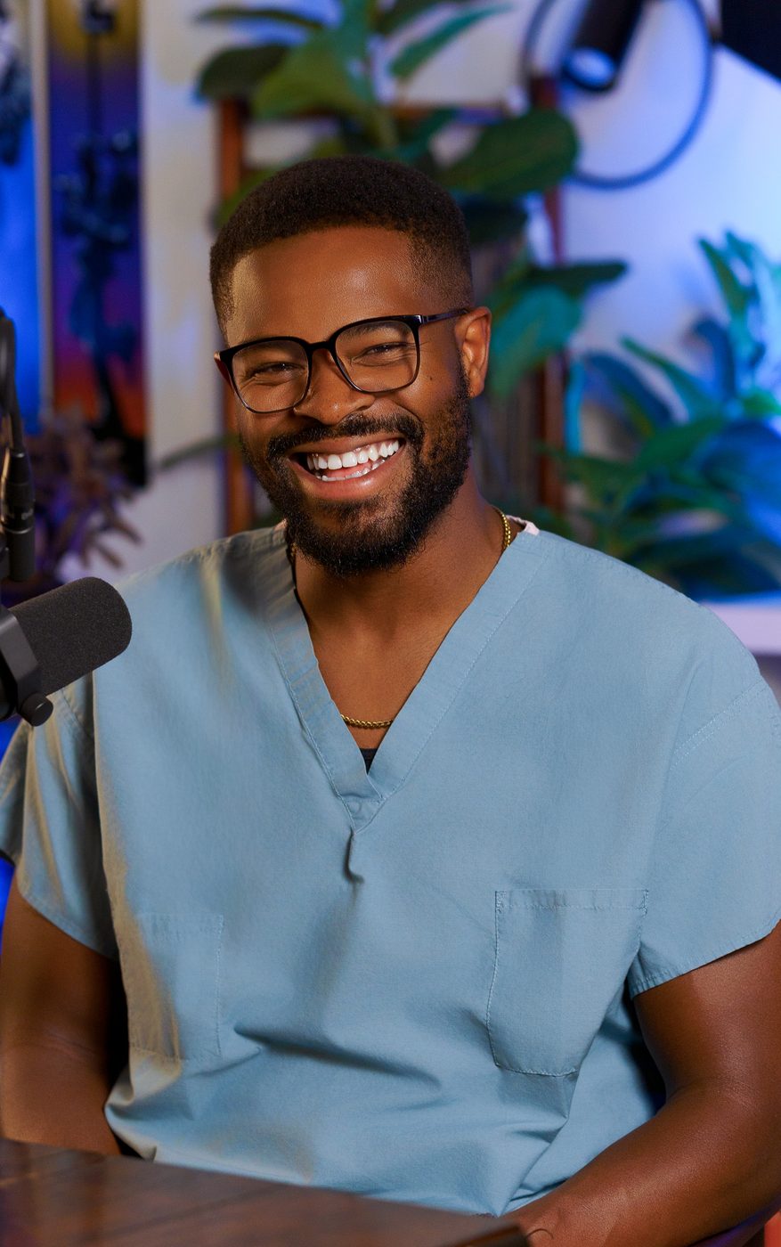 Dr. Ugo Ezema in blue scrubs holding a microphone